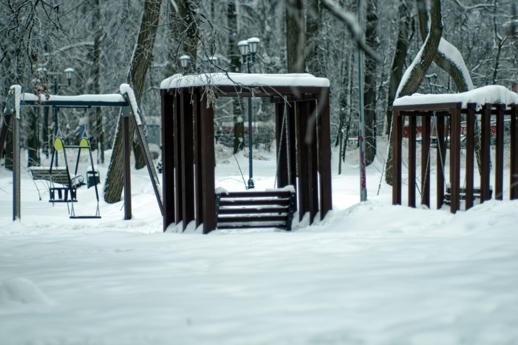 An empty children's playground in a snowy park