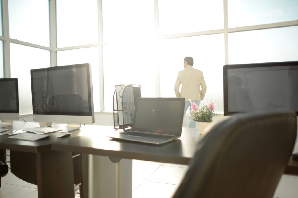 Office desks with computers and an employee standing by the window
