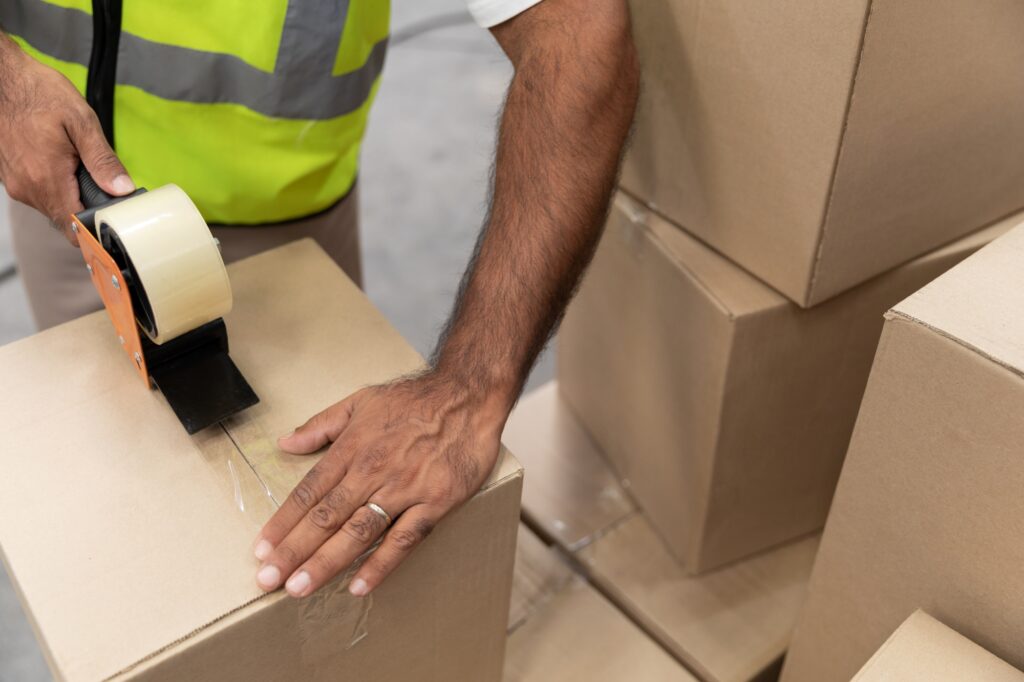 Cropped image of a professional home mover sealing the box